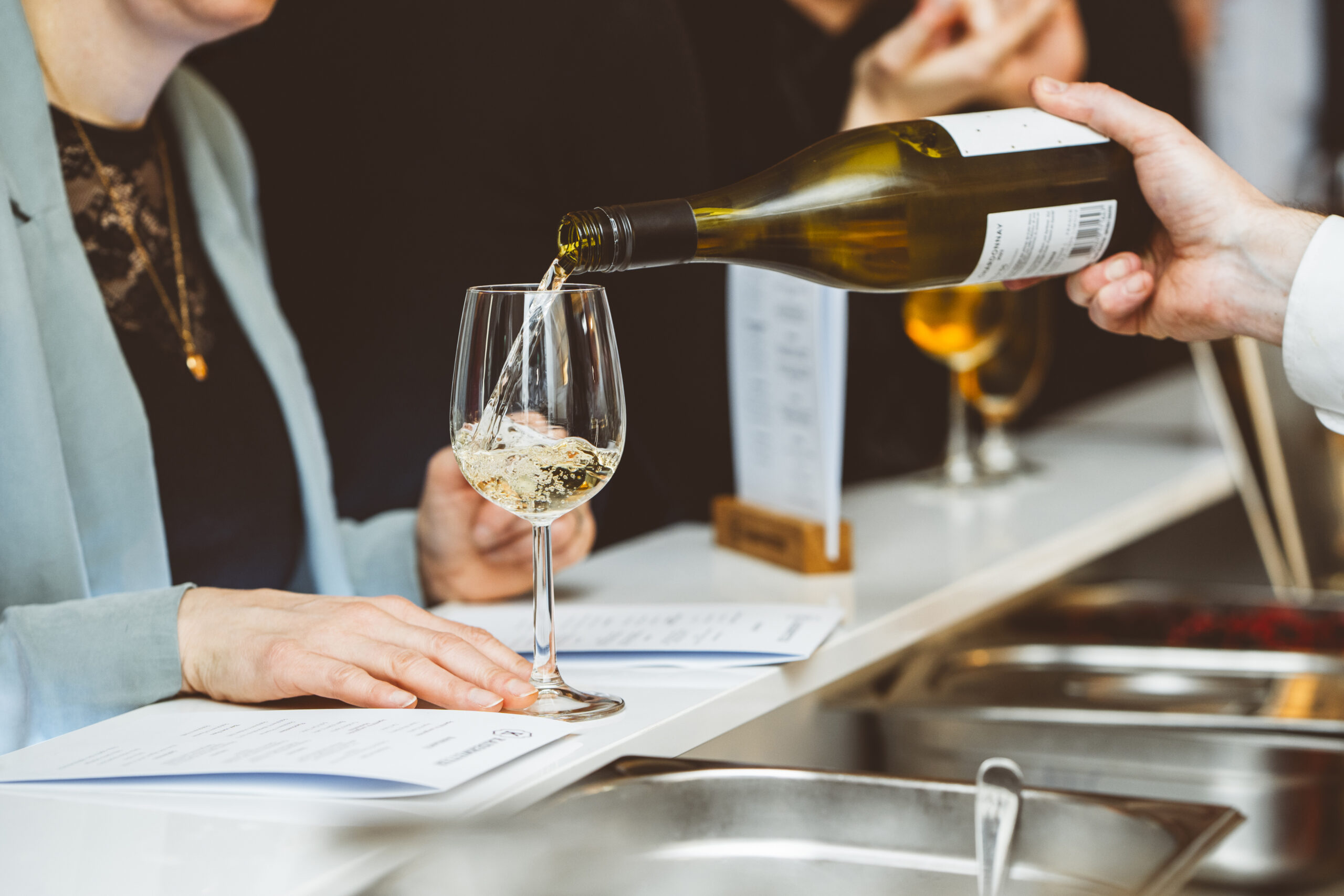 Ein Glas Wein wird aus der Flasche eingeschenkt | Drinks & Food beim Event Catering bei Kaiserwetter