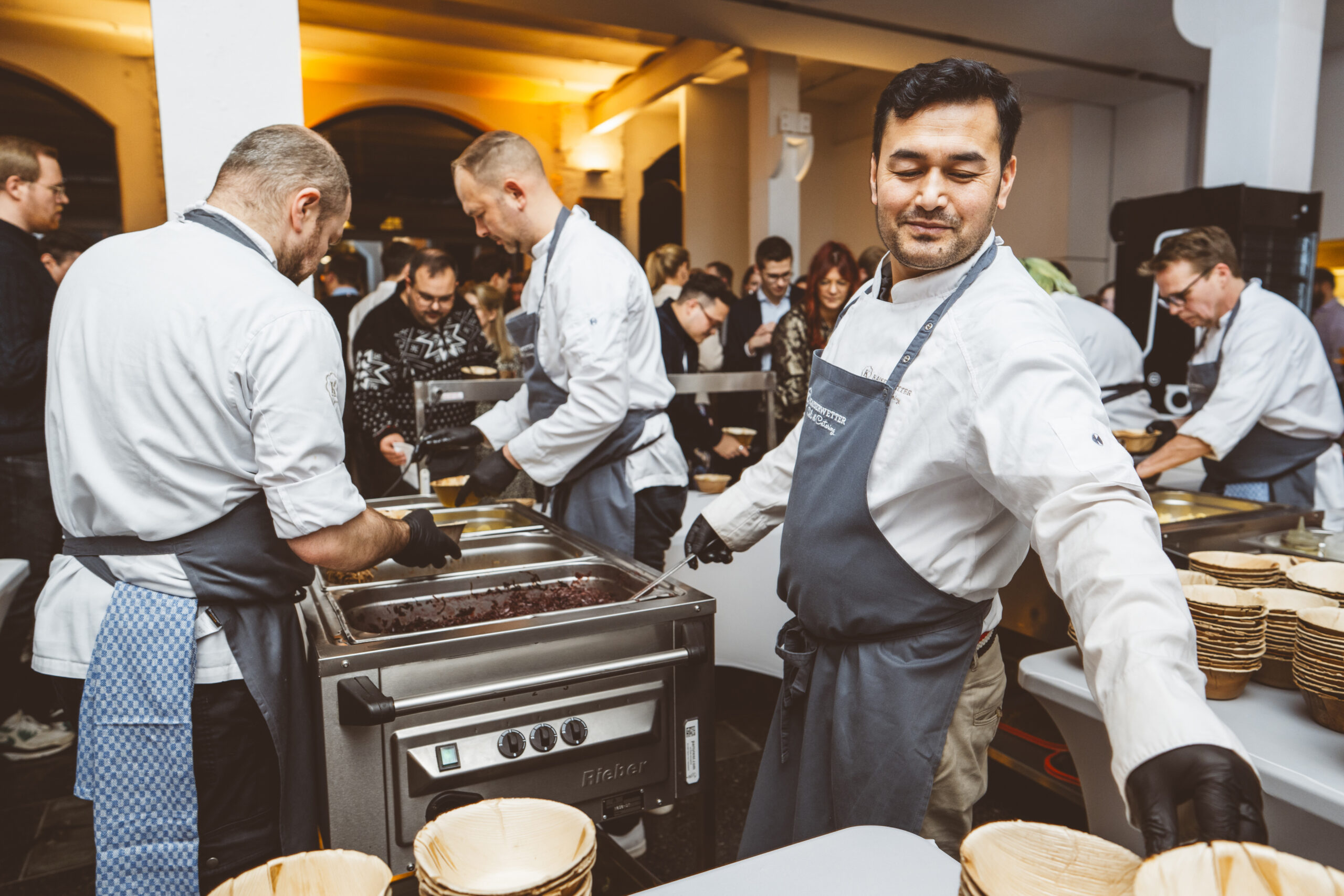 Servicepersonal steht an einem Catering Stand und gibt Essen aus | Event Catering von Kaiserwetter